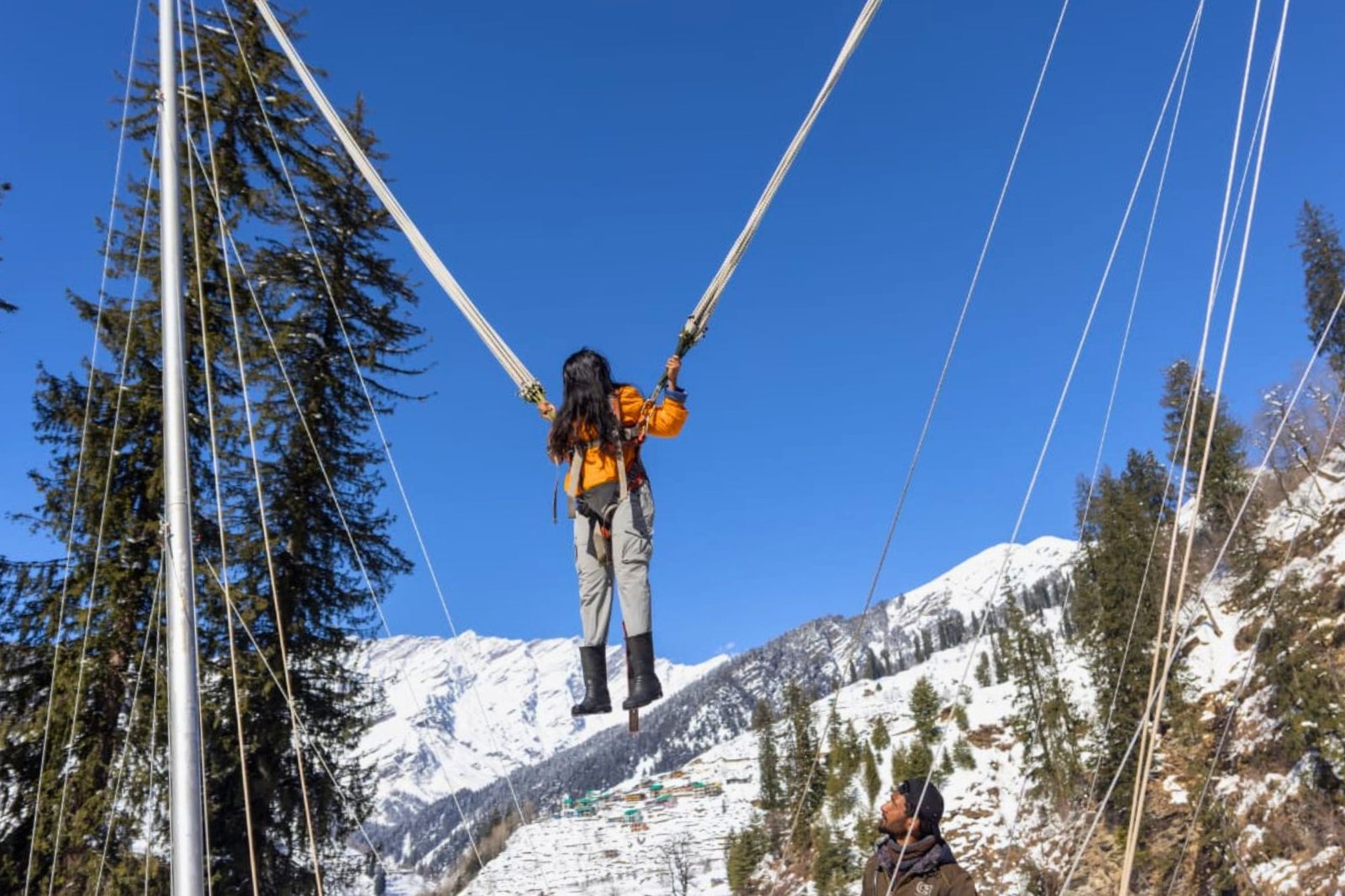 Woman bungee jumping with snowy mountains of manali and blue sky in the background