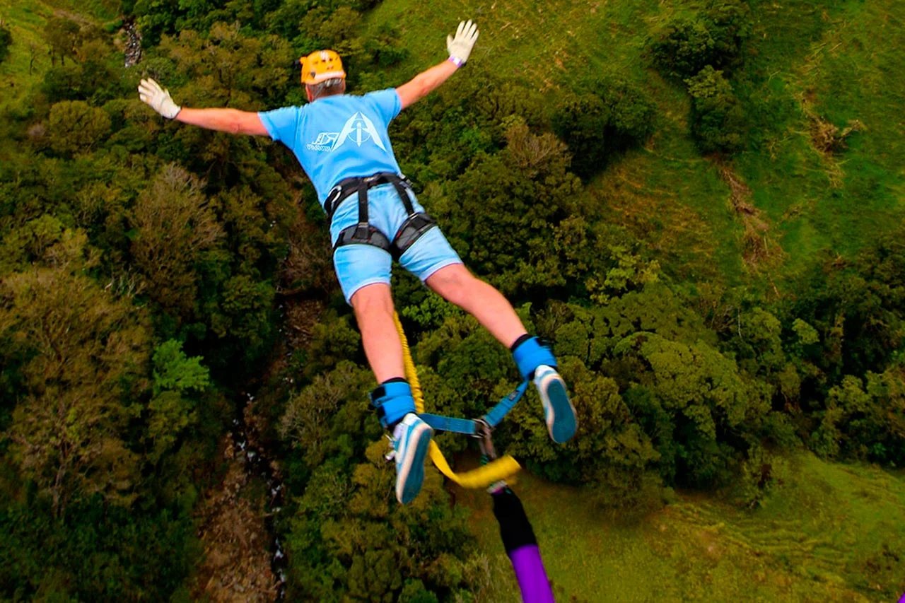  A man gliding on a zip line, experiencing the excitement of flight, accompanied by the slogan 7Feel The Rush.