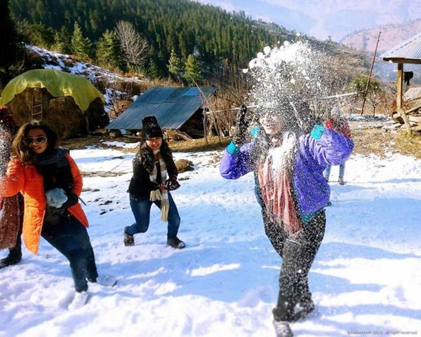 A group of female friends having a snowball fight in a snowy landscape of Manali