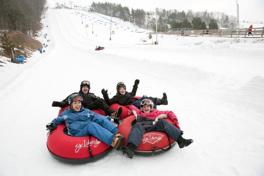 Group of people enjoying snow tubing in the winter season at Manali, surrounded by snowy mountains and crisp alpine air.