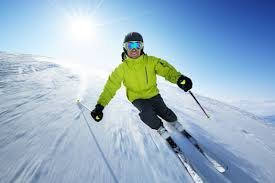 Skier in bright gear gliding down a snowy slope on a sunny day