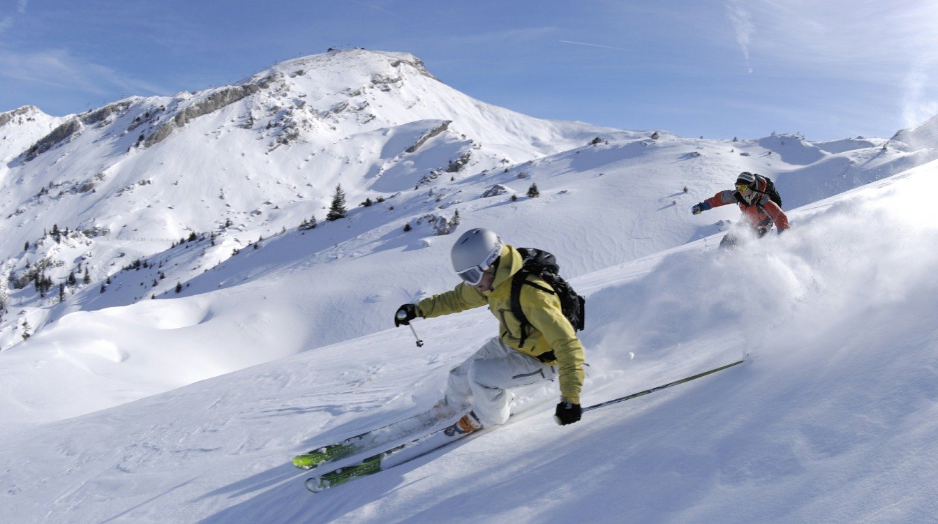 Two skiers navigating a snowy mountain slope under clear skies